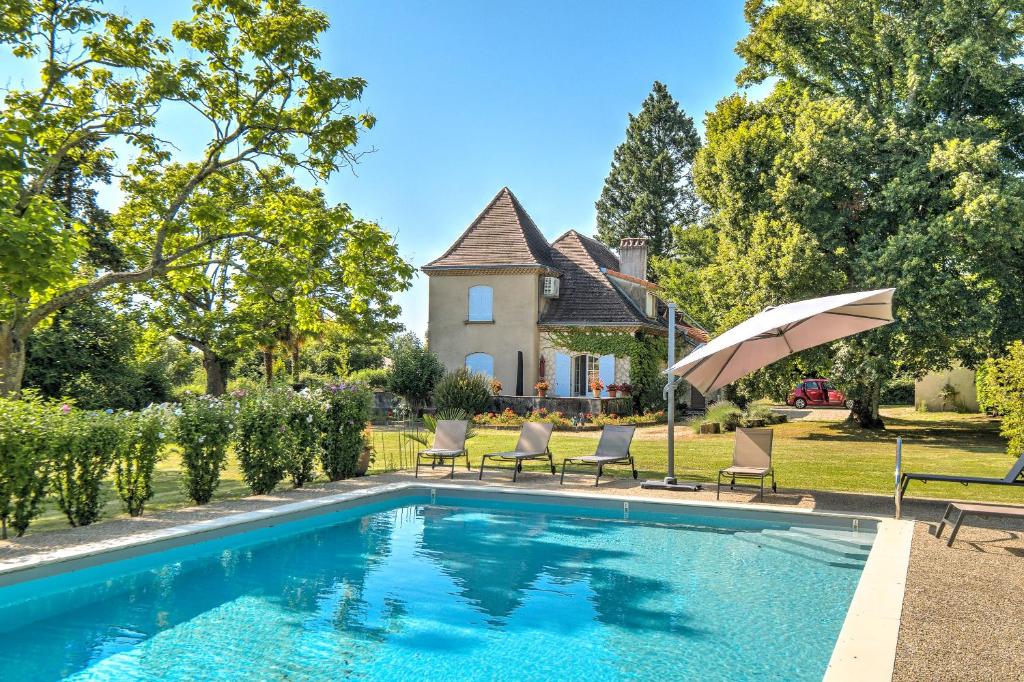 a pool with chairs and an umbrella in front of a house at Magnifique maison à Ribérac in Ribérac