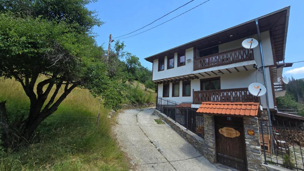 a building with a fence next to a road at Къща за гости Начовата къща Стойките, Пампорово in Vodata