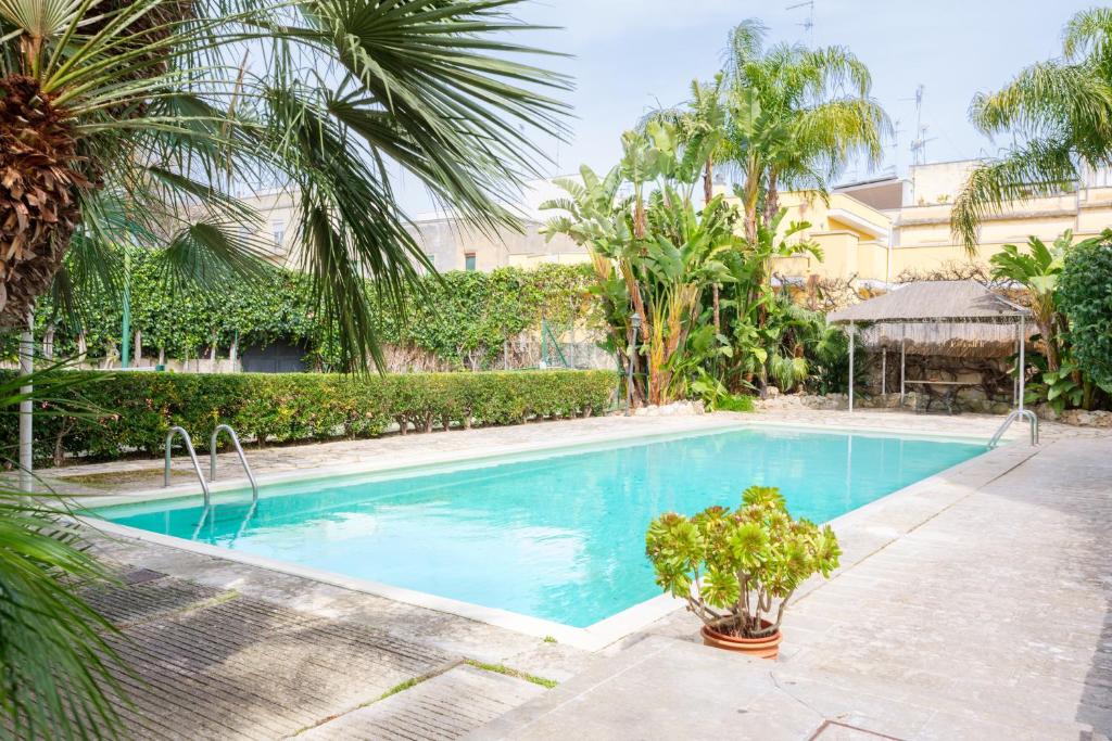 a swimming pool with palm trees and a building at Gli Archi with pool - Lecce in Lecce