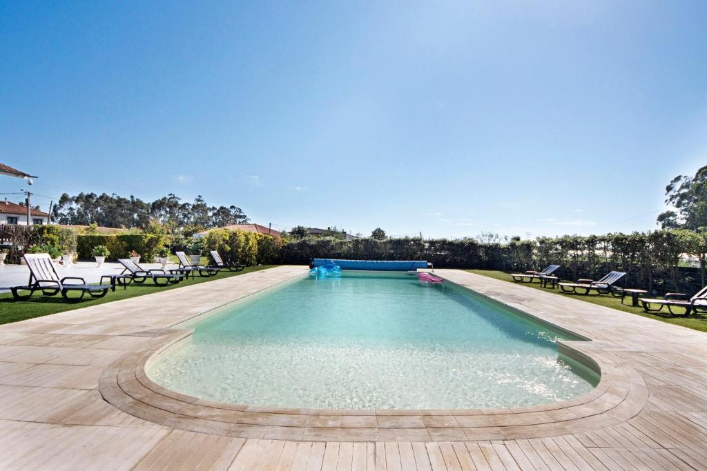 a large swimming pool with chairs in a yard at Apartamento Thaï com Piscina in Apúlia