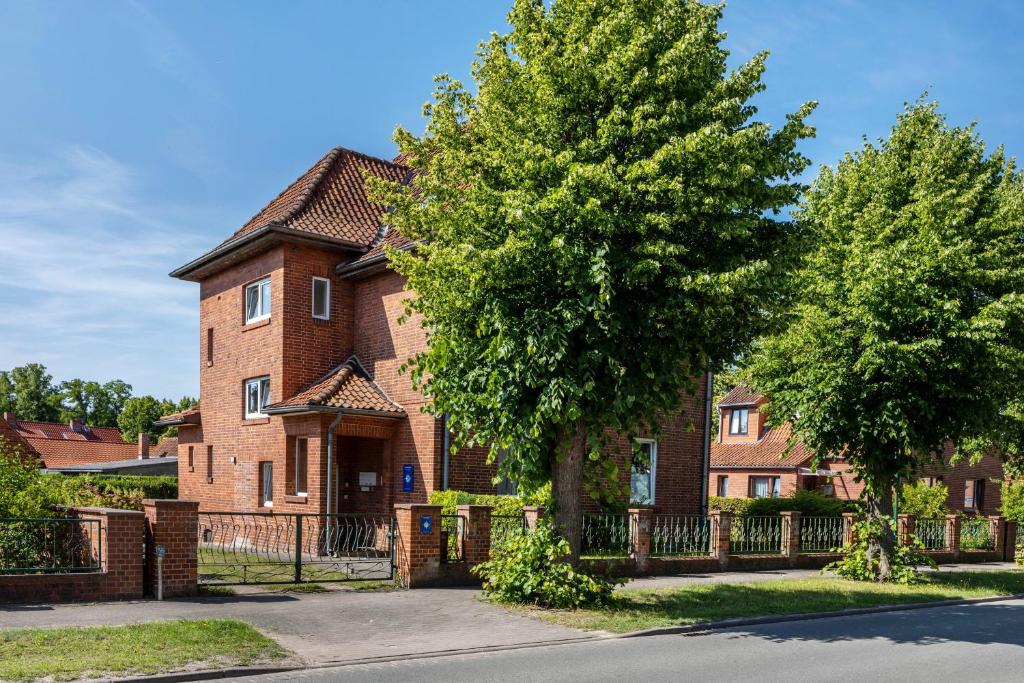 a brick house with a fence and a tree at Ferienwohnung Stella Maris in Carrenzien