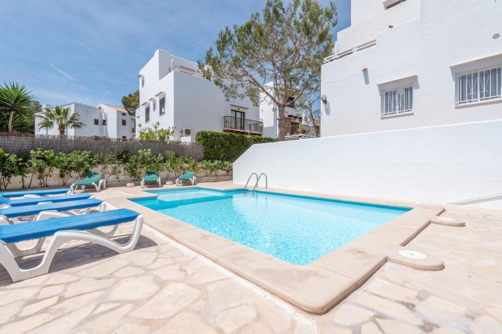 a swimming pool with chaise lounge chairs next to a building at Apartamentos Karin 1ºc in Cala d´Or