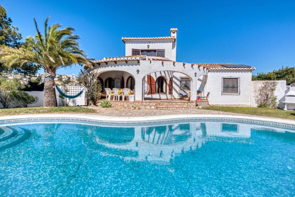 a villa with a swimming pool in front of a house at Entre Caballos in Cumbre del Sol