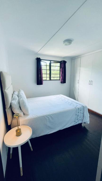 a bedroom with a bed with a table and a window at Badumetsie cottage in Durban