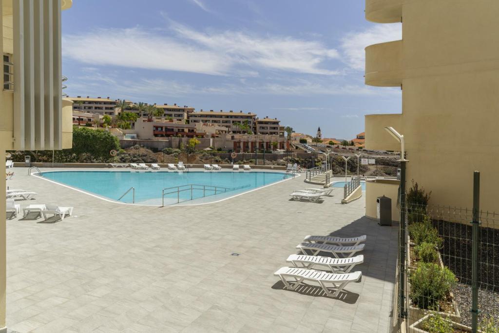 a large swimming pool with lounge chairs next to a building at Apartamento Sol Paraiso in Adeje
