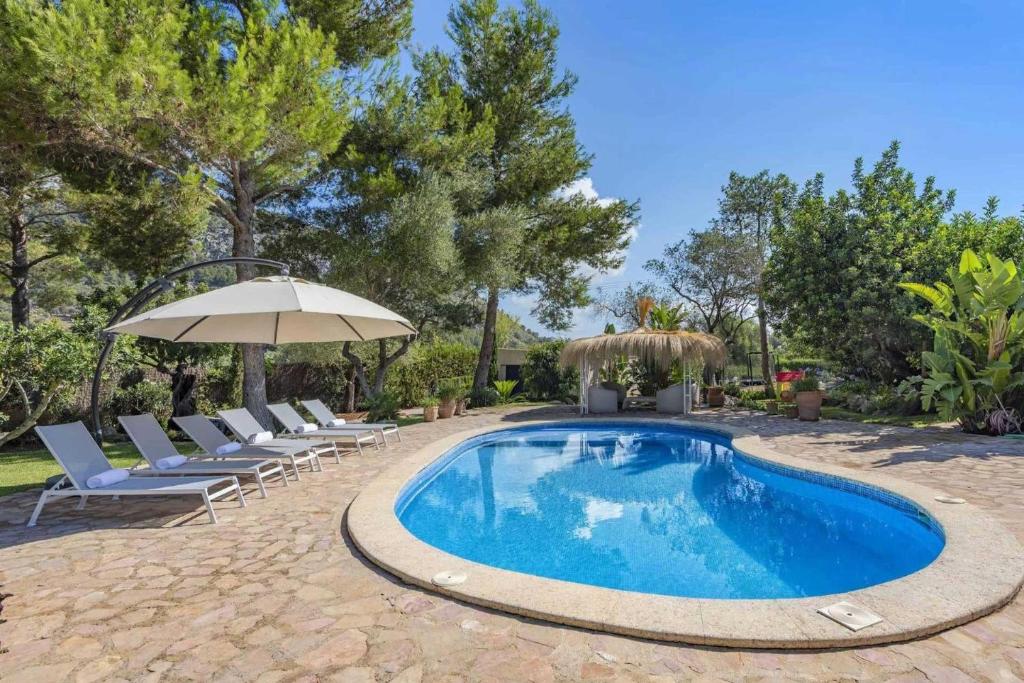 a swimming pool with chairs and an umbrella at Can Verd Vall De Colonya in Pollença