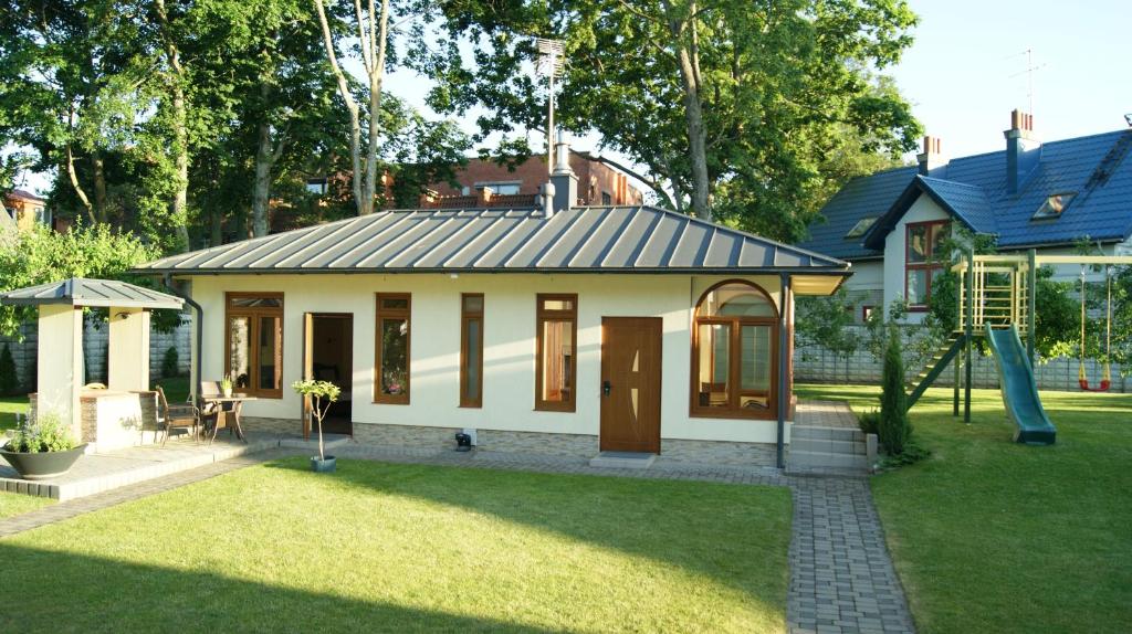 a small house with a playground in a yard at VilaFėja Private courtyard house in Palanga