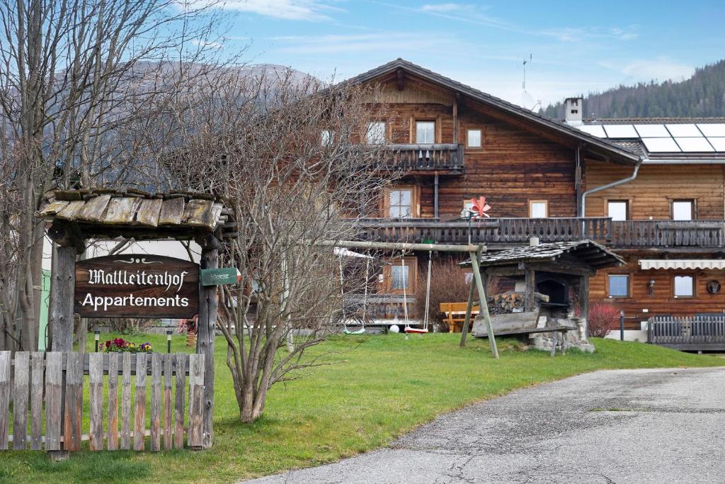a large wooden house with a sign in front of it at Mattleitenhof in Santa Maddalena