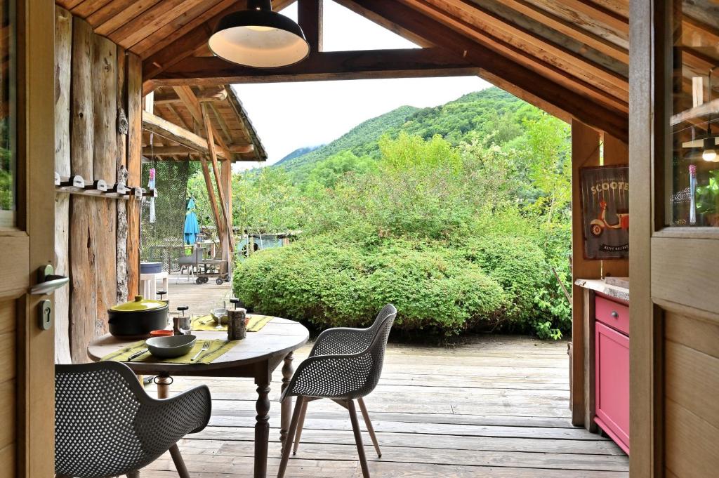 a patio with a table and chairs on a deck at Cabane Myrtille in Arrien-en-Bethmale