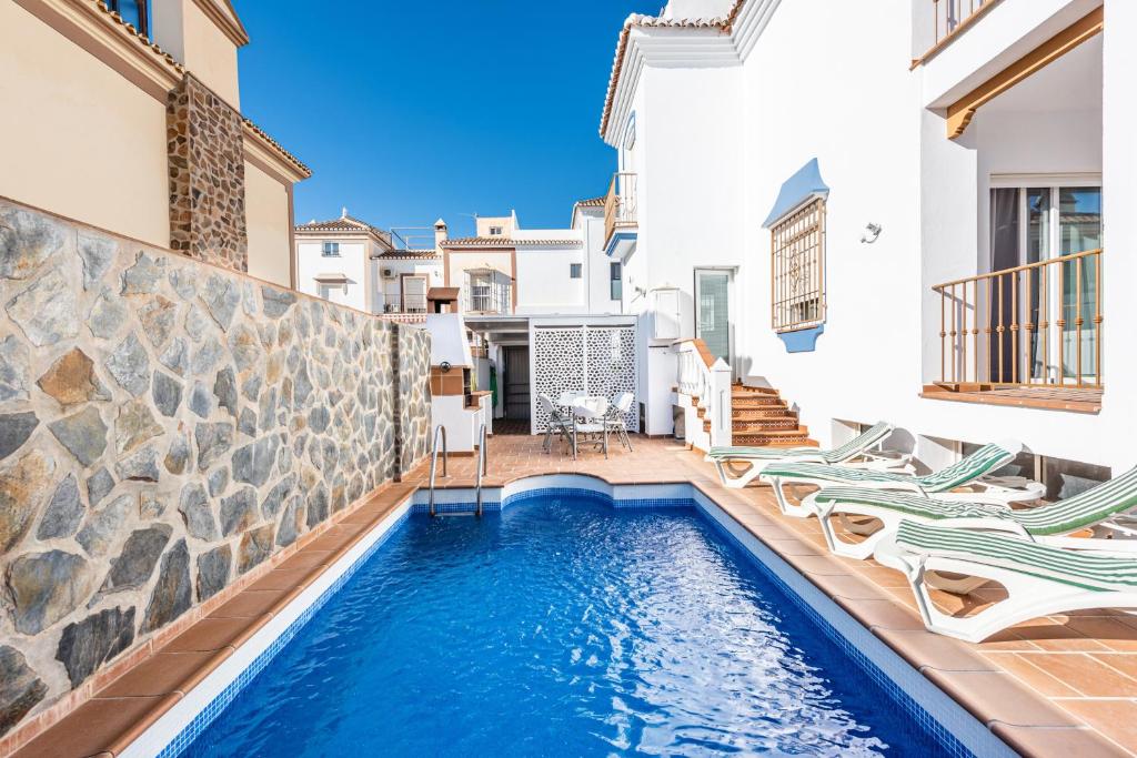 a swimming pool in a villa with two lawn chairs at Villa Zoe in Nerja