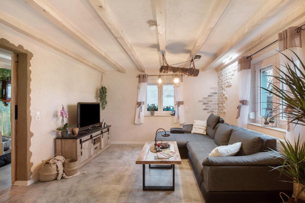 a living room with a couch and a tv at kernsaniertes Ferienhaus Anna in Durlangen