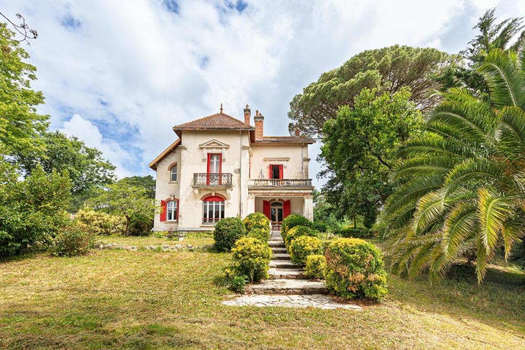an old house with red windows and a staircase in front at Etage maison bourgeoise dans Parc in Soorts-Hossegor
