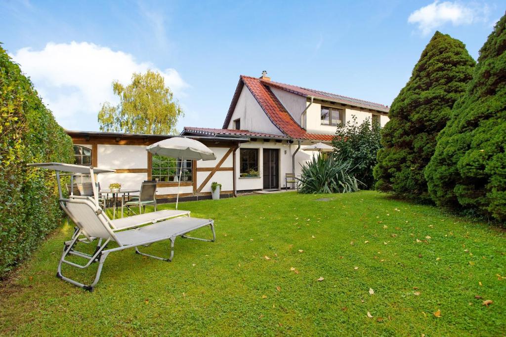 a house with a lawn with a chair and an umbrella at Ferienwohnung To Hus in Putbus
