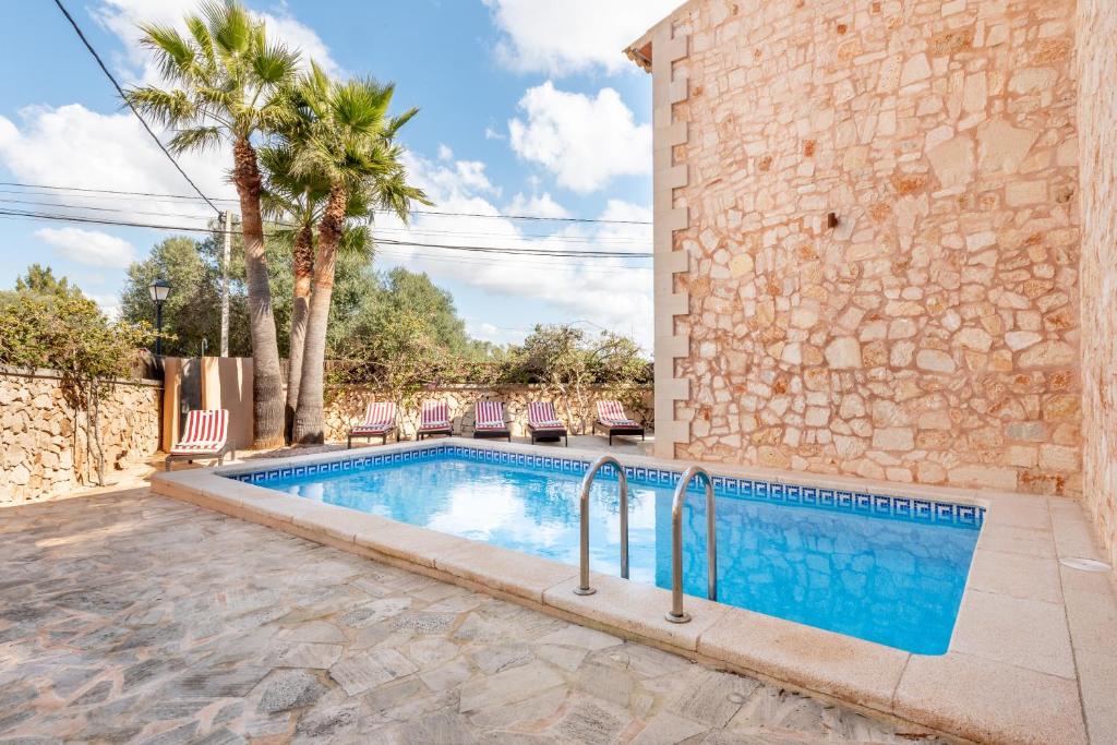 a swimming pool with chairs next to a building at Es Cantó in Cala Llombards