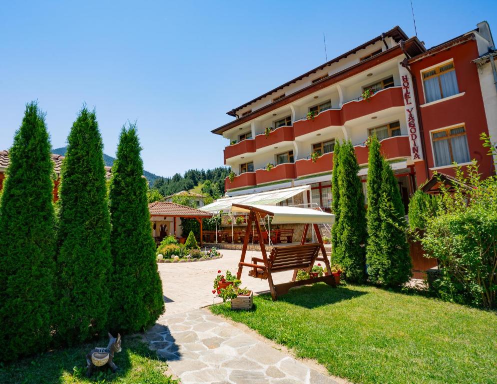 a hotel with an umbrella and a garden at Yagodina Family Hotel in Yagodina