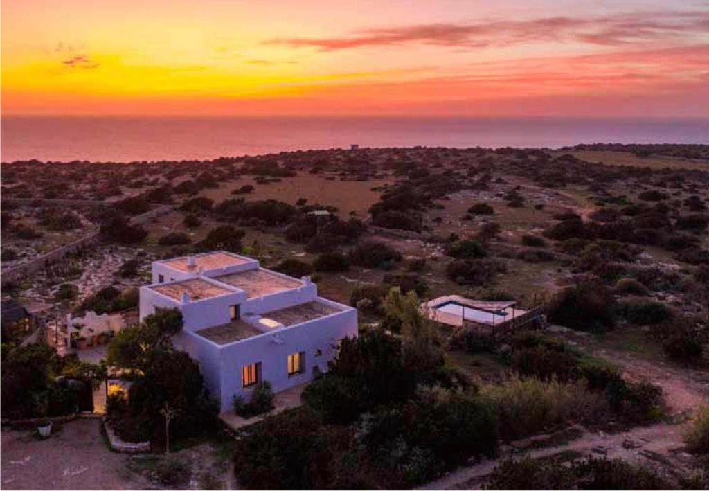 a house in a field with a sunset in the background at Can Picca in Illes Balears