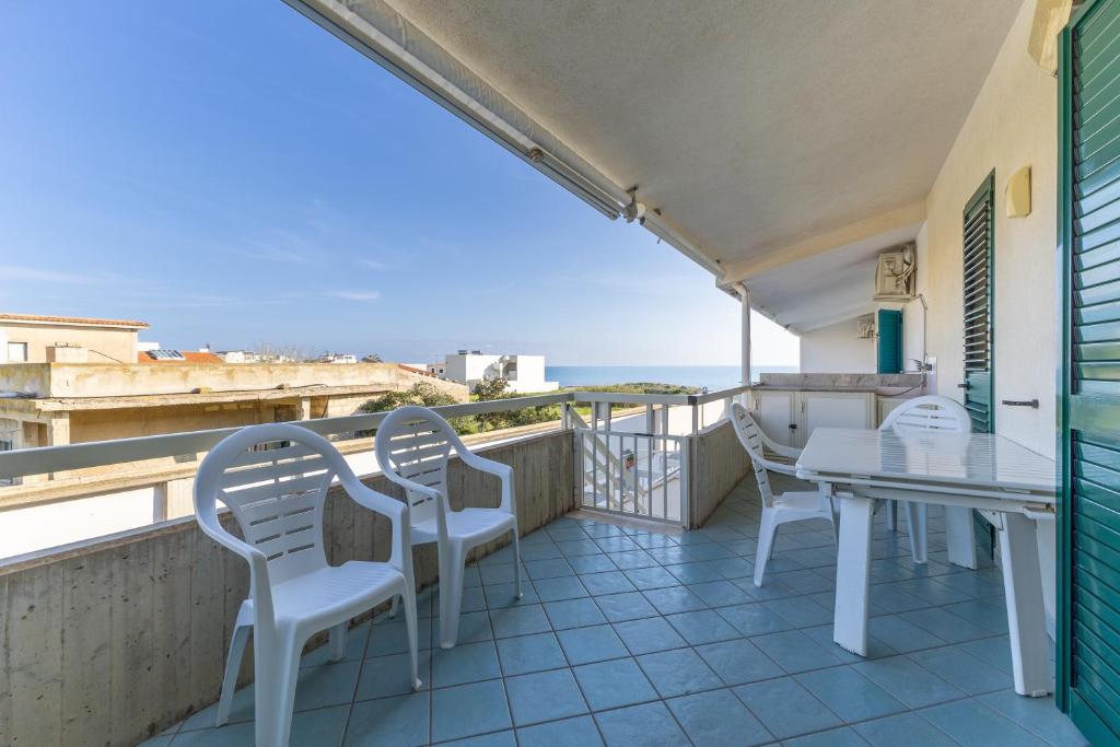 a balcony with white chairs and a table and the ocean at Vista Mare in Santa Croce Camerina