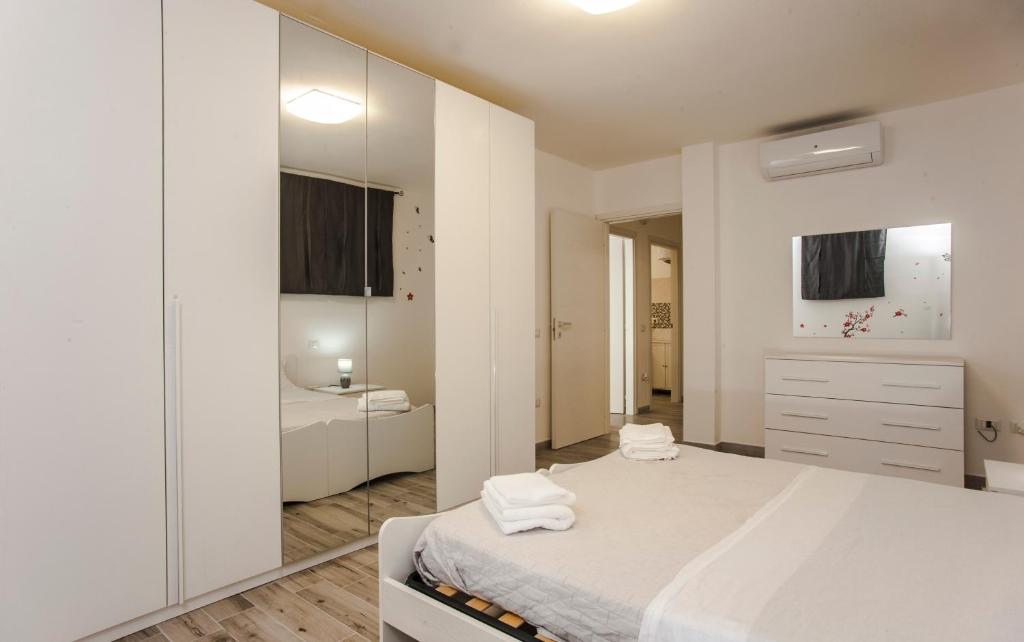 a white bedroom with a bed and a bathroom at Villetta farfalle in Sarroch