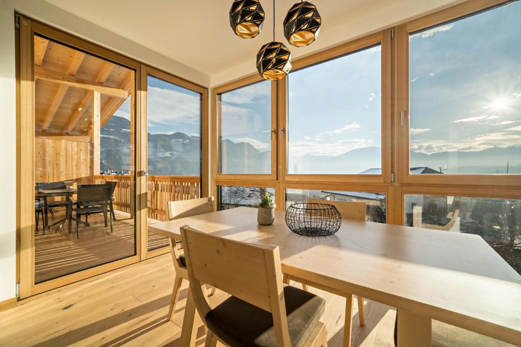 a dining room with a table and chairs and large windows at Apt Eiche - Nockerhof in Andrian
