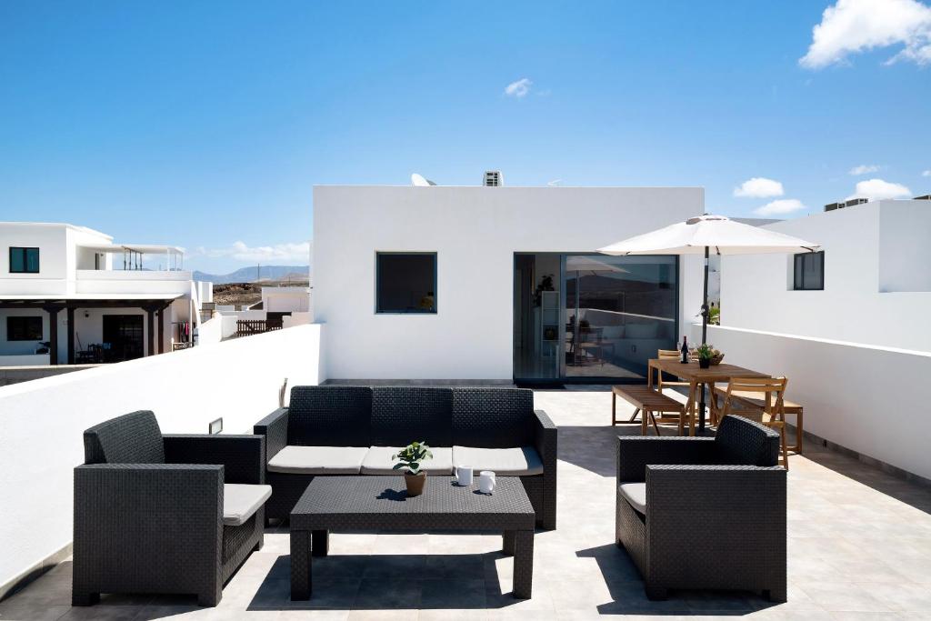 a rooftop patio with chairs and tables and an umbrella at Brisa 3 in La Santa