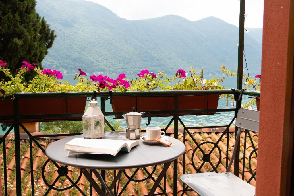 a table with a book on a balcony with flowers at Fogazzaro Lake View Apartment in Oria
