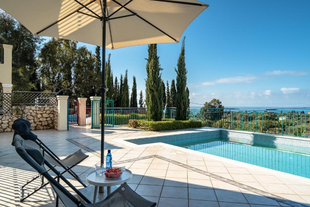a patio with a table and an umbrella next to a pool at Villa Millianna Exclusive Apartment in Kefallonia