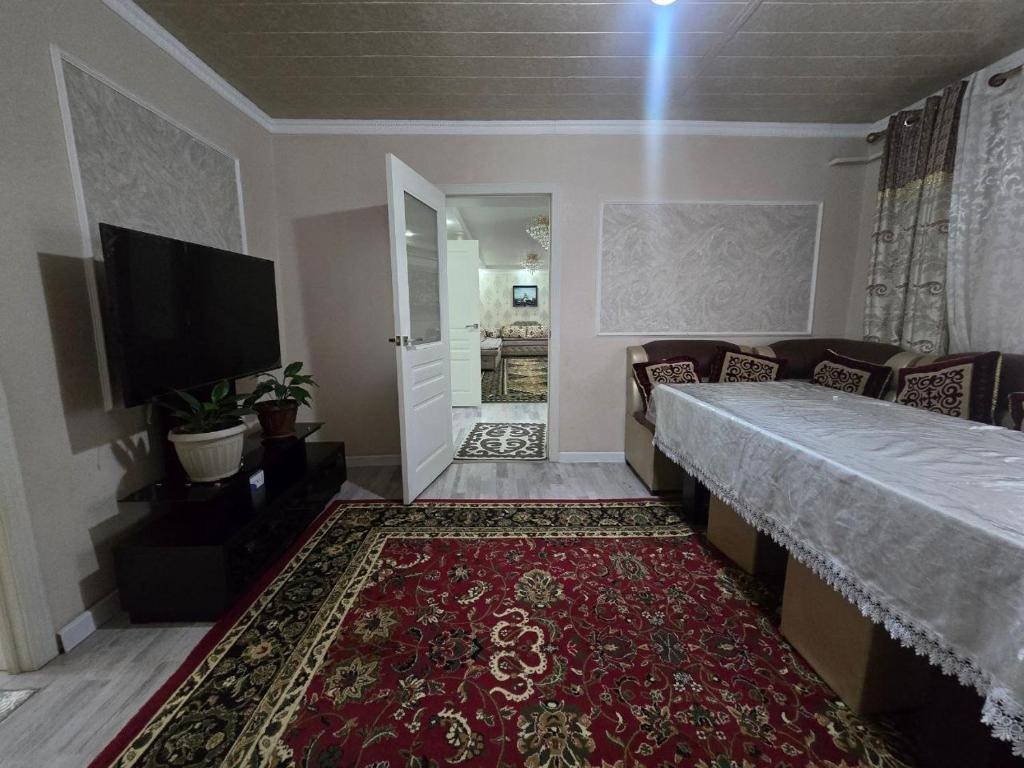 a living room with a couch and a tv and a rug at Azis Hostel in Karatëbë