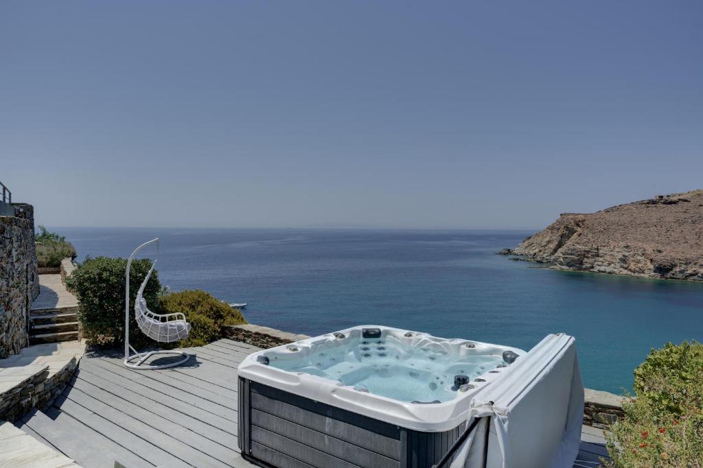 a hot tub on a deck next to the ocean at Blueros - Sand Suite in Megas Gialos - Nites