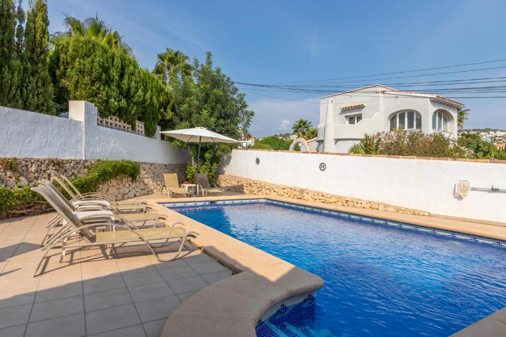 a swimming pool with chairs and a house at Villa Margarita in Benissa