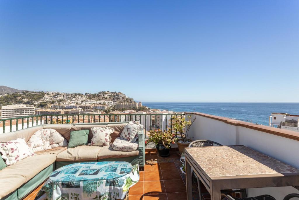 a balcony with a couch and a table and the ocean at Casa Mia in Almuñécar