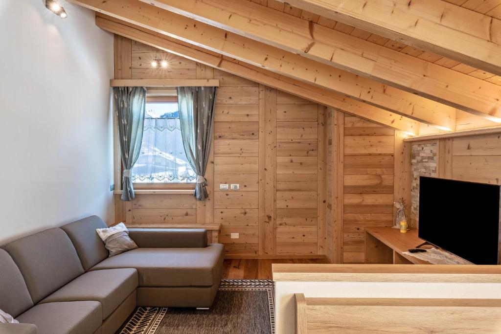 a living room with a couch and a tv at Luxury Apartment Majon de Rita in Vigo di Fassa