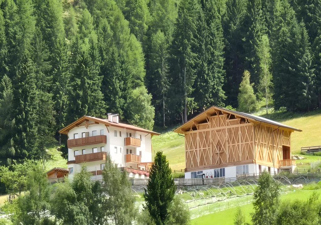 ein Gebäude inmitten eines Feldes mit Bäumen in der Unterkunft Pirchahof in Martell