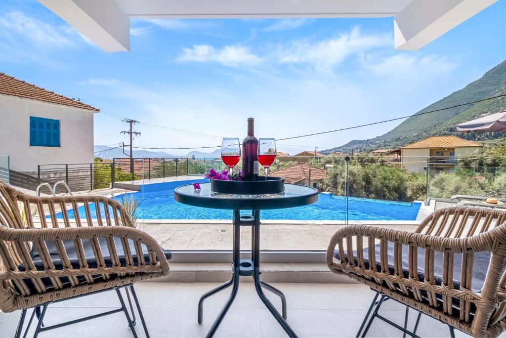 a table with two glasses of wine sitting between two chairs at Oceanida Afrodite Lyxury Suite in Nikiana