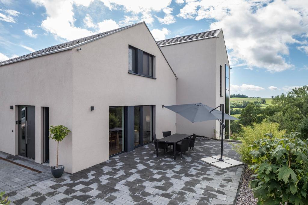 a white house with a black table and an umbrella at Gold Haus in Weilheim