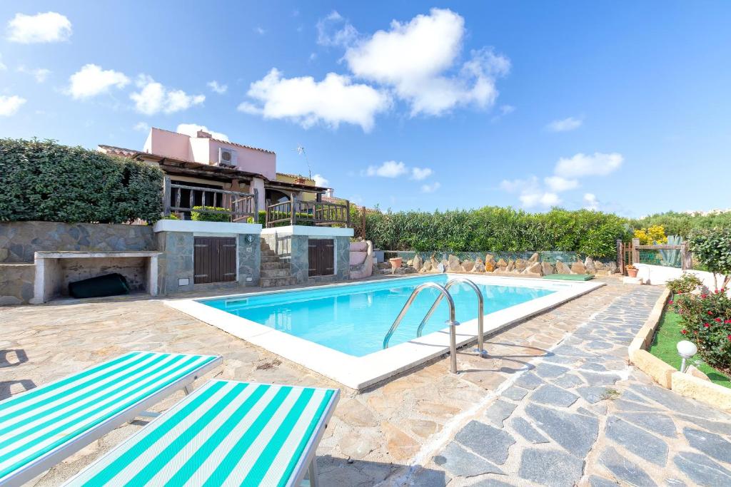 a swimming pool with two benches in front of a house at Villa Sofia in Cuile Pazzoni