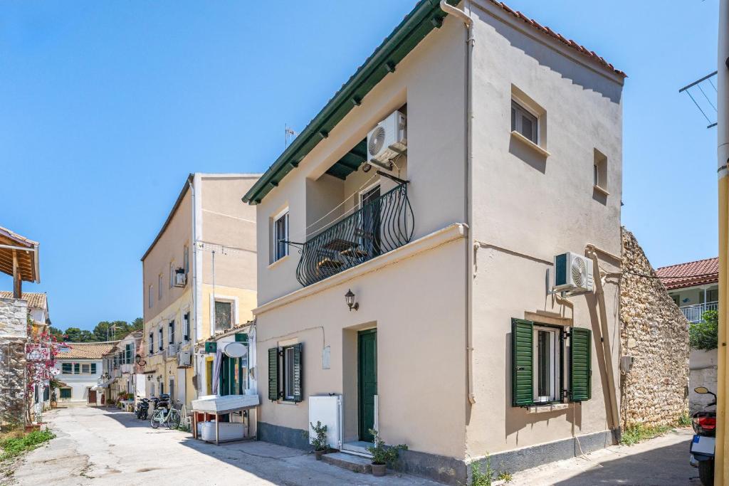 a white building with green shutters on a street at Casa Di Babis in Gaios