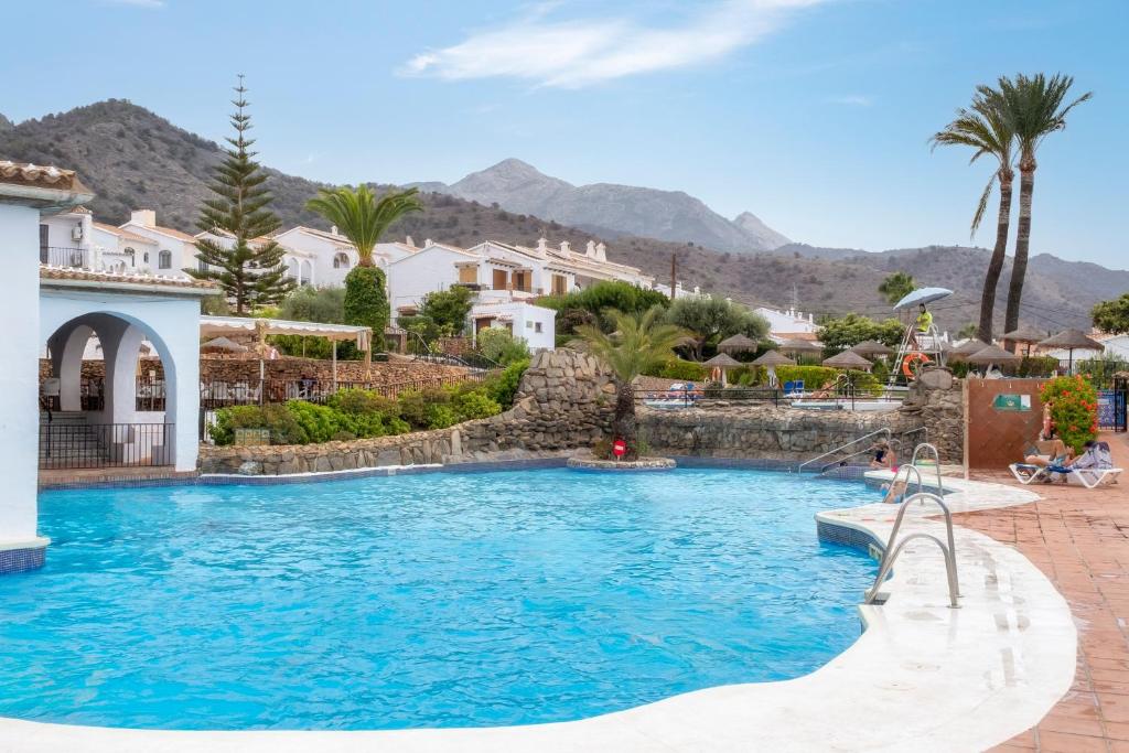 a pool at a resort with mountains in the background at Dalias Nerja in Nerja