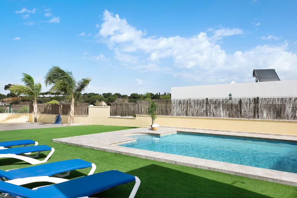 a swimming pool with lounge chairs in a yard at Villa Montenmedio - Juande in El Soto