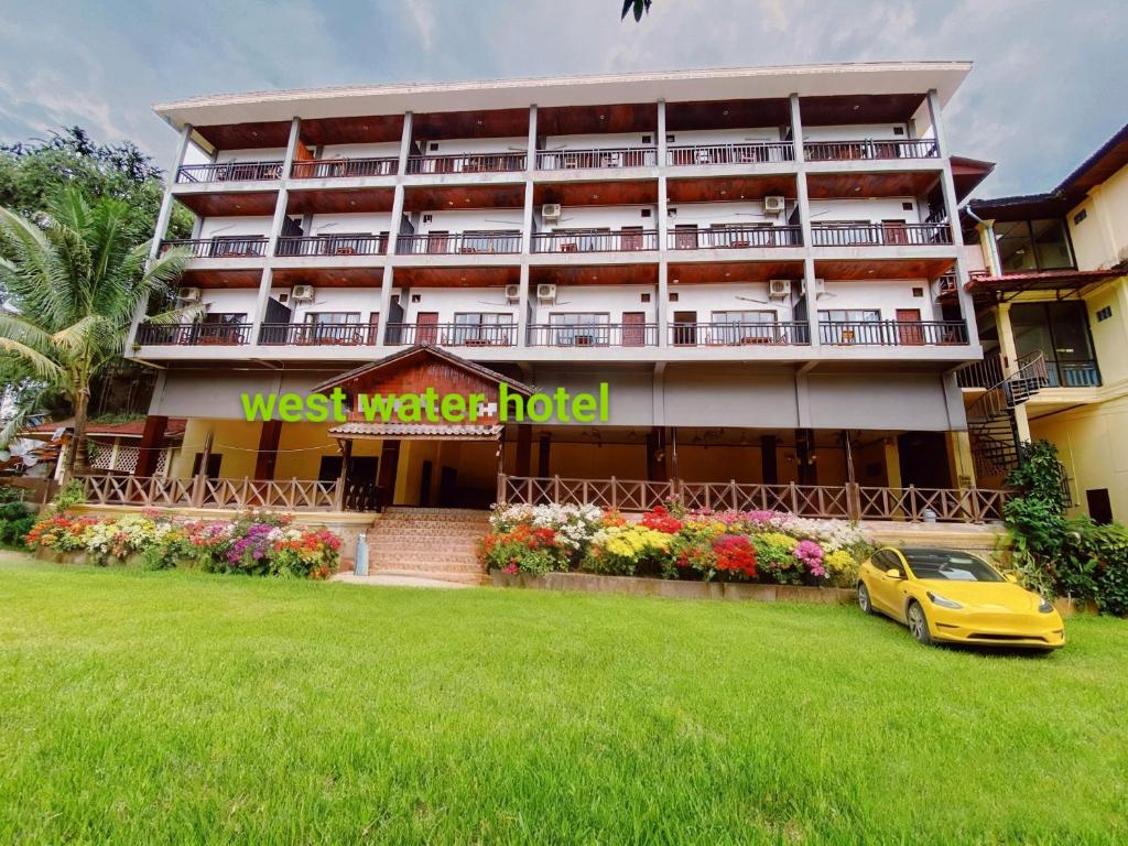 a hotel with a yellow car parked in front of it at west water hotel in Vang Vieng