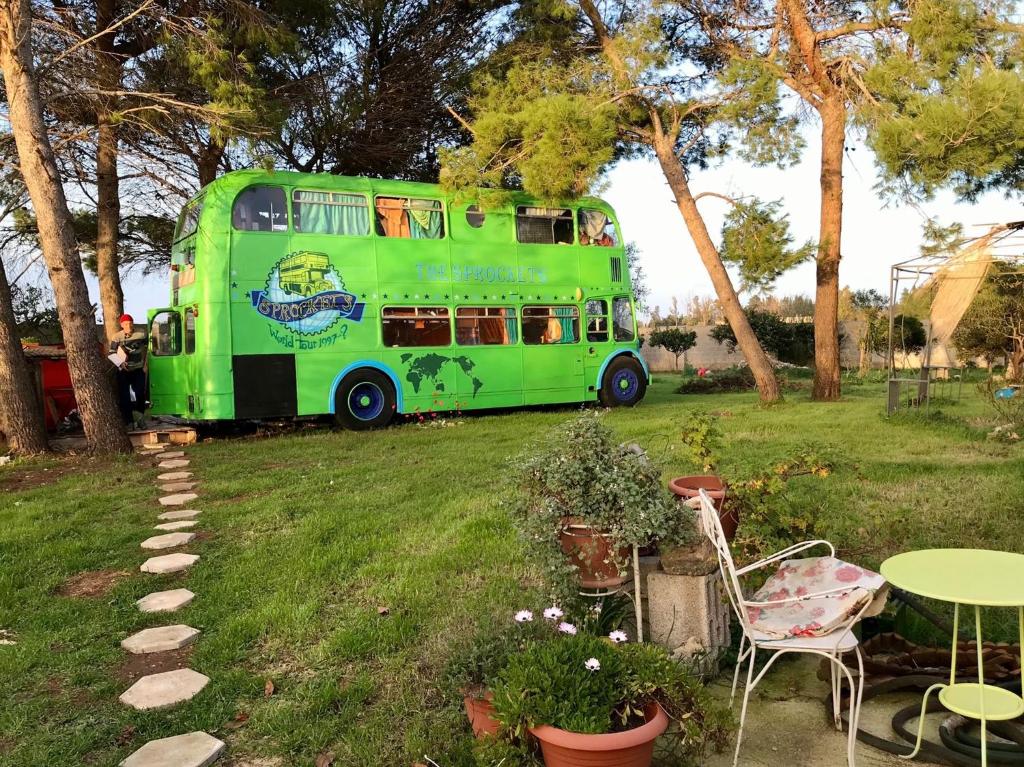 a green double decker bus parked in a yard at Sprocketlandia in Frigole