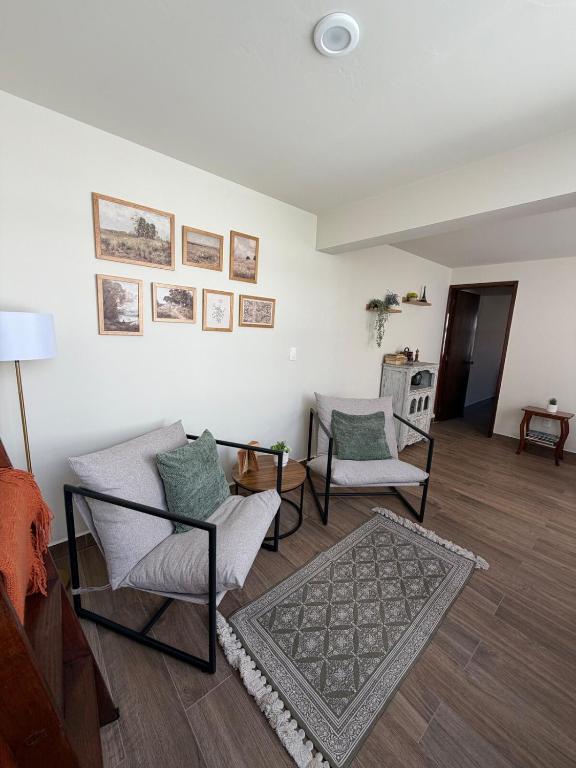 a living room with two chairs and a rug at Spacious house just steps from the cathedral in Morelia