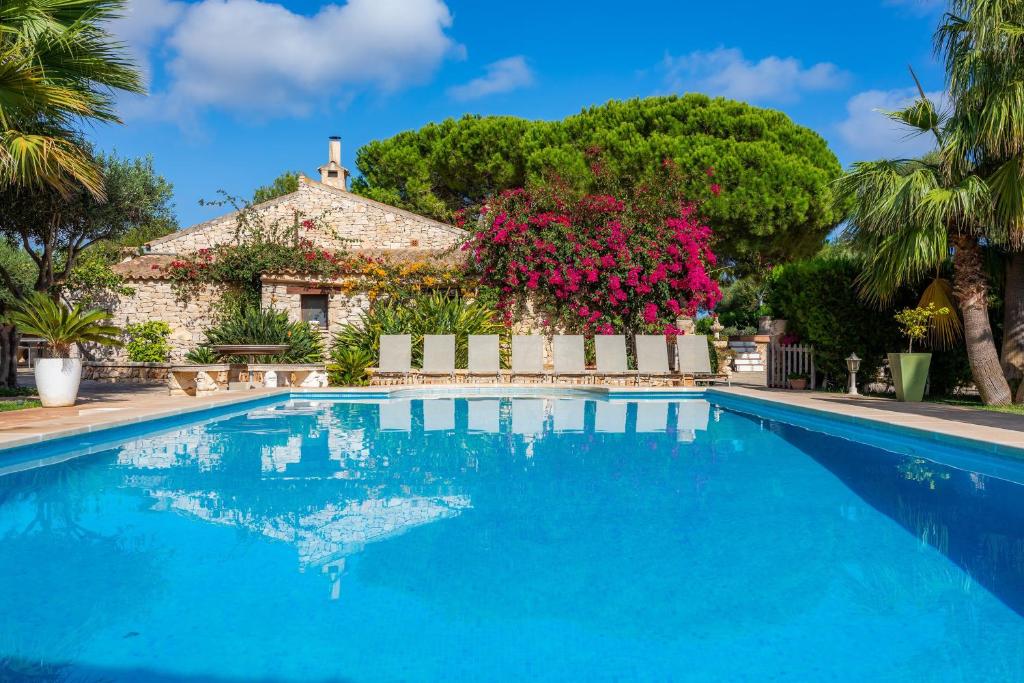 a villa with a swimming pool in front of a house at Ses Rodes in Felanitx