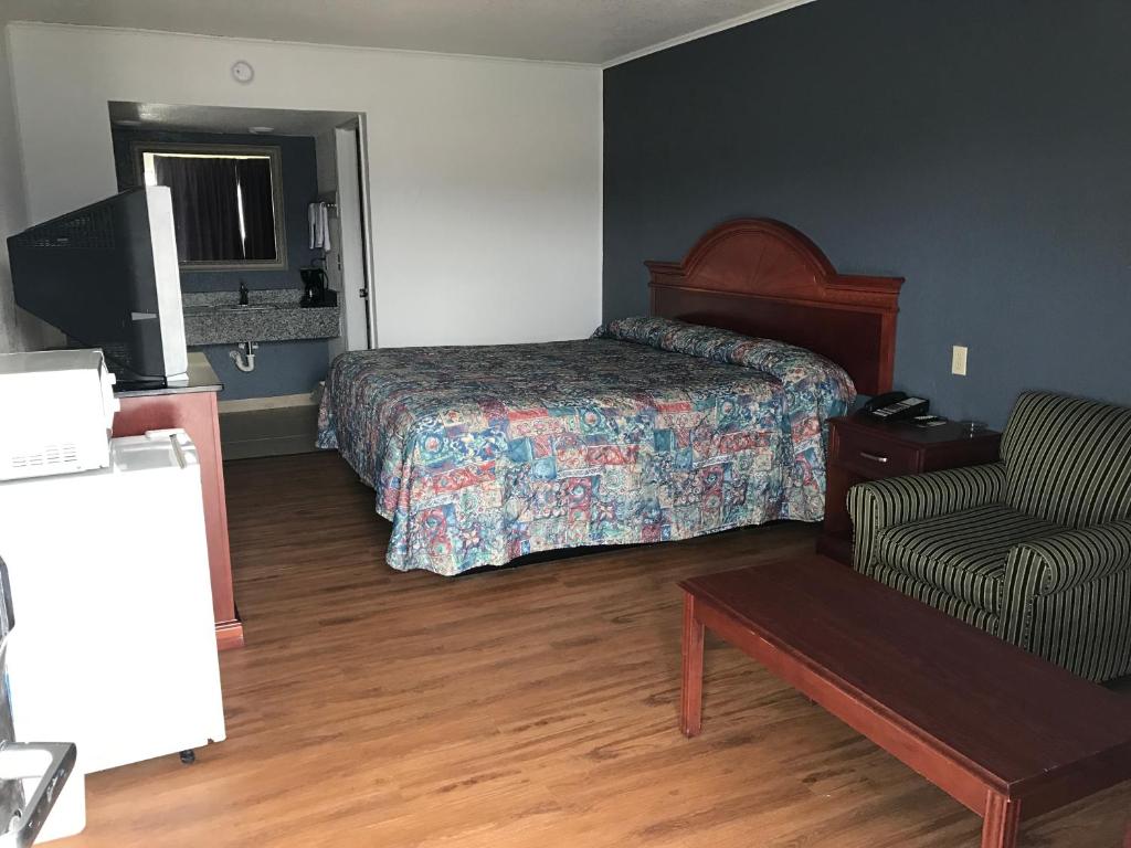 a hotel room with a bed and a chair at Sallisaw Inn in Sallisaw