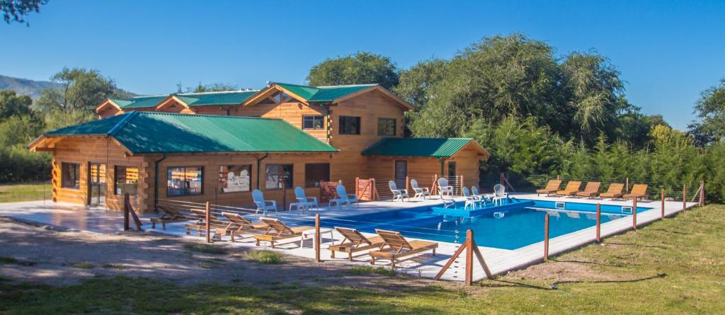 een blokhut met een zwembad en een huis bij Del Milagro Cabañas & Posada in Villa General Belgrano