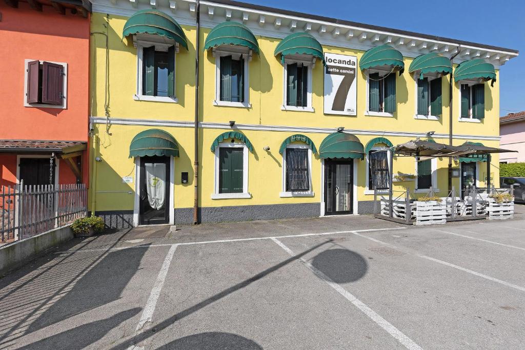 a yellow building with green awnings in a parking lot at B and B 7 Camini in Verona