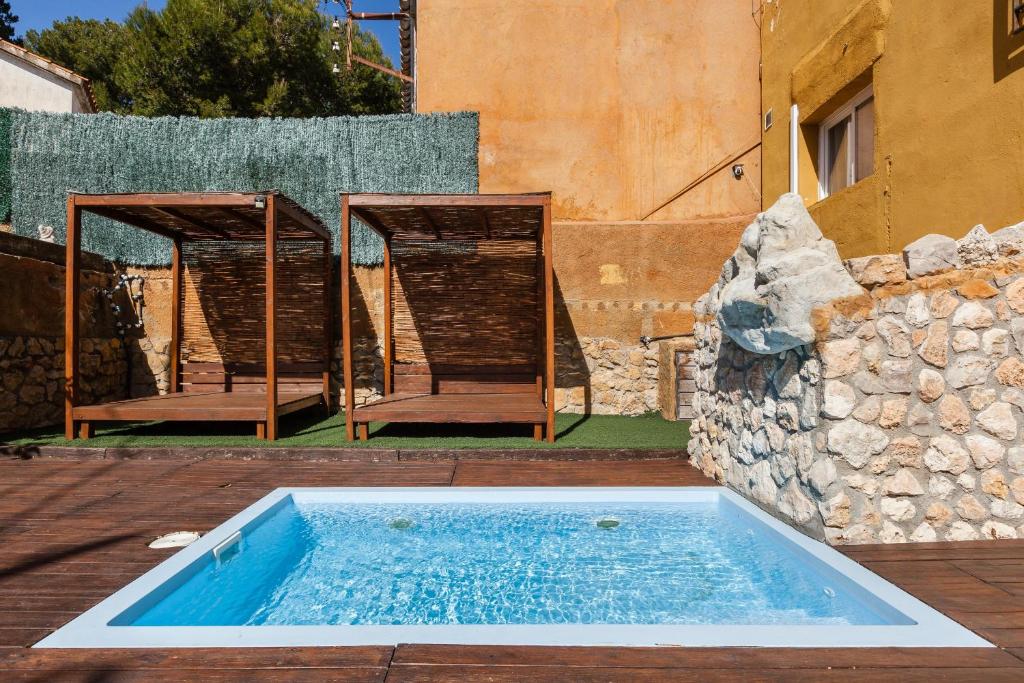 a swimming pool with two chairs at Masia Alt in Olerdola