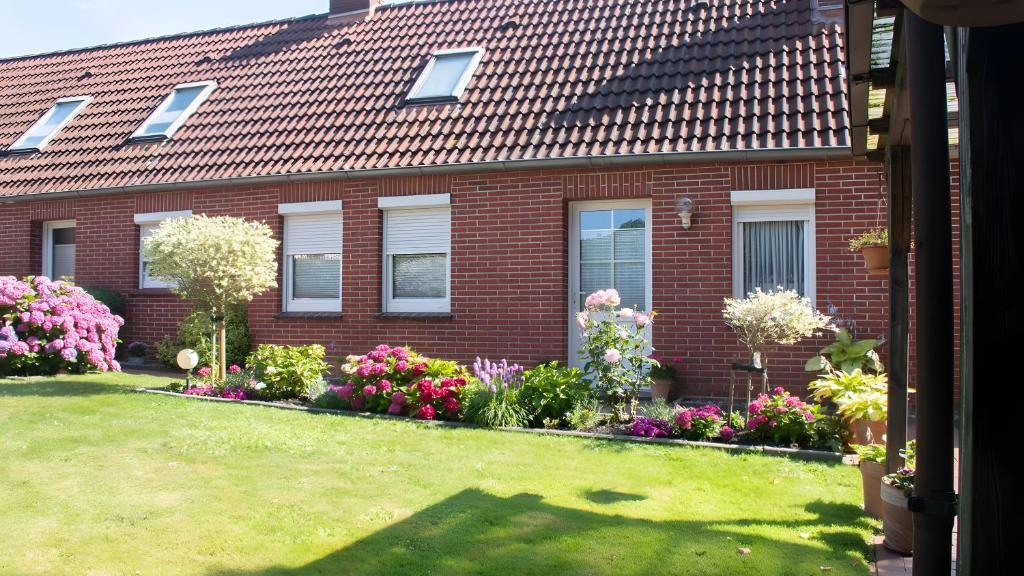 a red brick house with flowers in the yard at Ferienwohnung Schmidt in Krummhörn