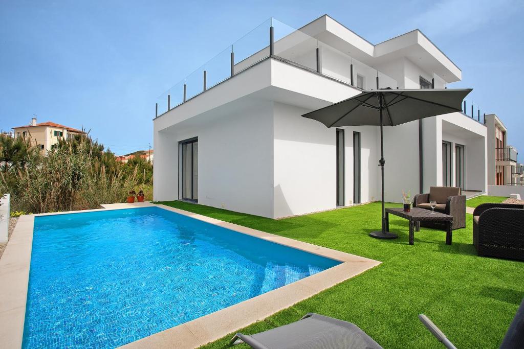 a villa with a swimming pool and an umbrella at Villa Atlantic View in Salir de Porto