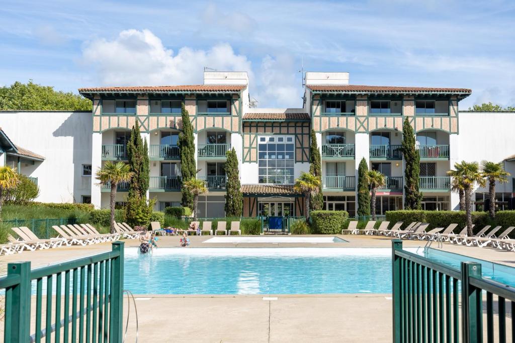 a hotel with a swimming pool in front of a building at Appartement Bisbau in Moliets-et-Maa