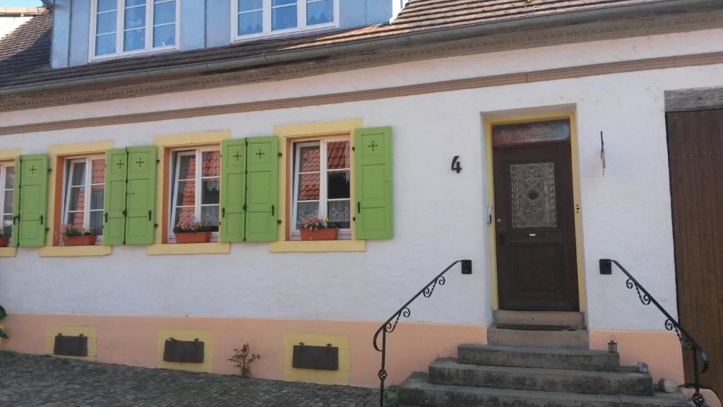 a white house with green shuttered windows and stairs at Ferienwohnung Sternenhof in Breisach am Rhein